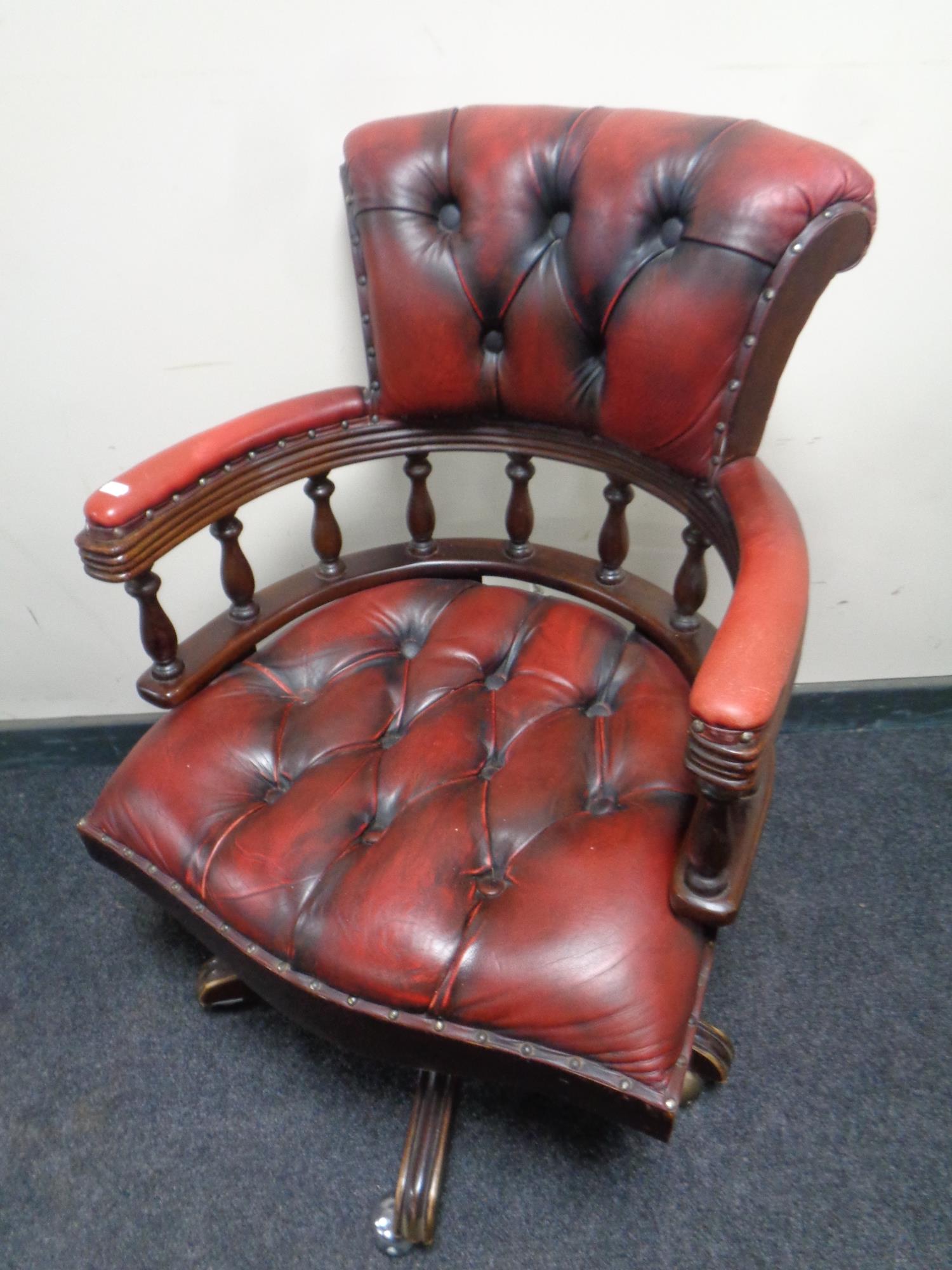 An oxblood buttoned leather captains armchair