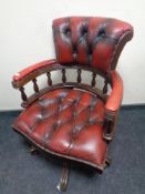 An oxblood buttoned leather captains armchair