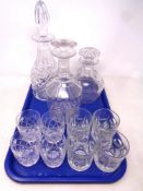 A tray containing three cut glass decanters with stoppers together with two sets of whiskey glasses