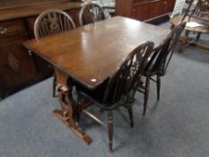 An oak refectory dining table together with a set of four wheel back dining chairs and matching