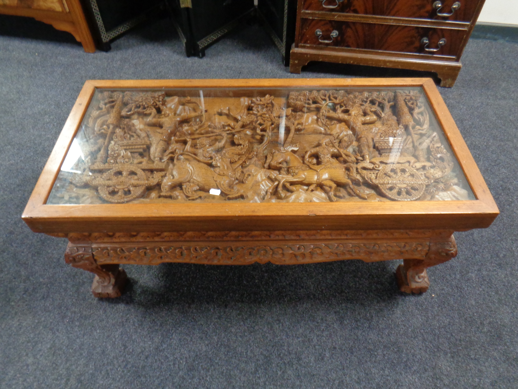 A heavily carved Thai rectangular coffee table with glass top
