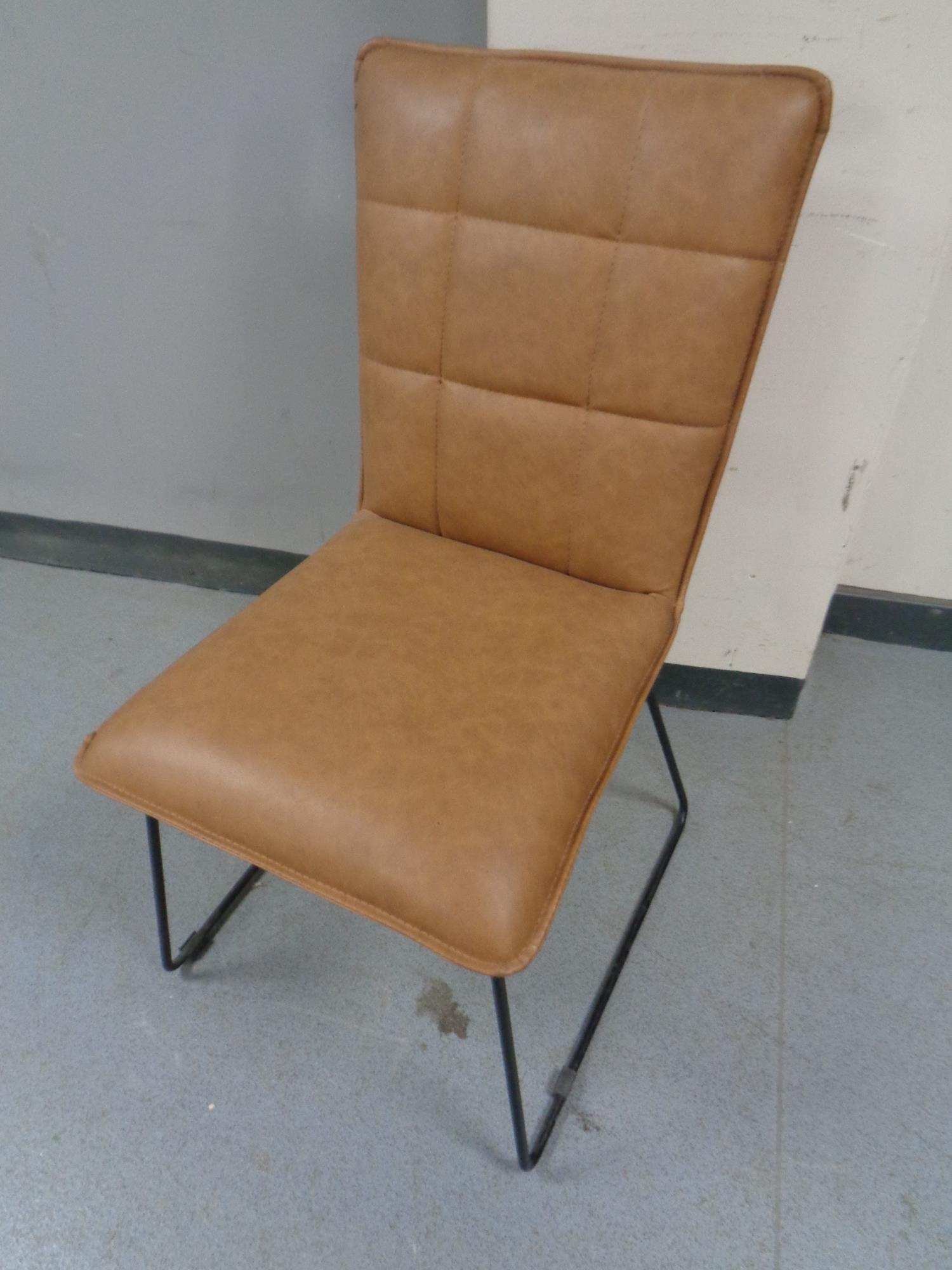 A contemporary brown leather dining chair on metal legs