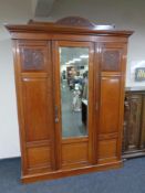 A 19th century mahogany triple door wardrobe with central mirror paneled door fitted trays
