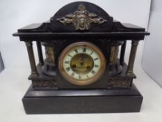 A 19th century brass and black slate mantel clock with brass and enamel dial