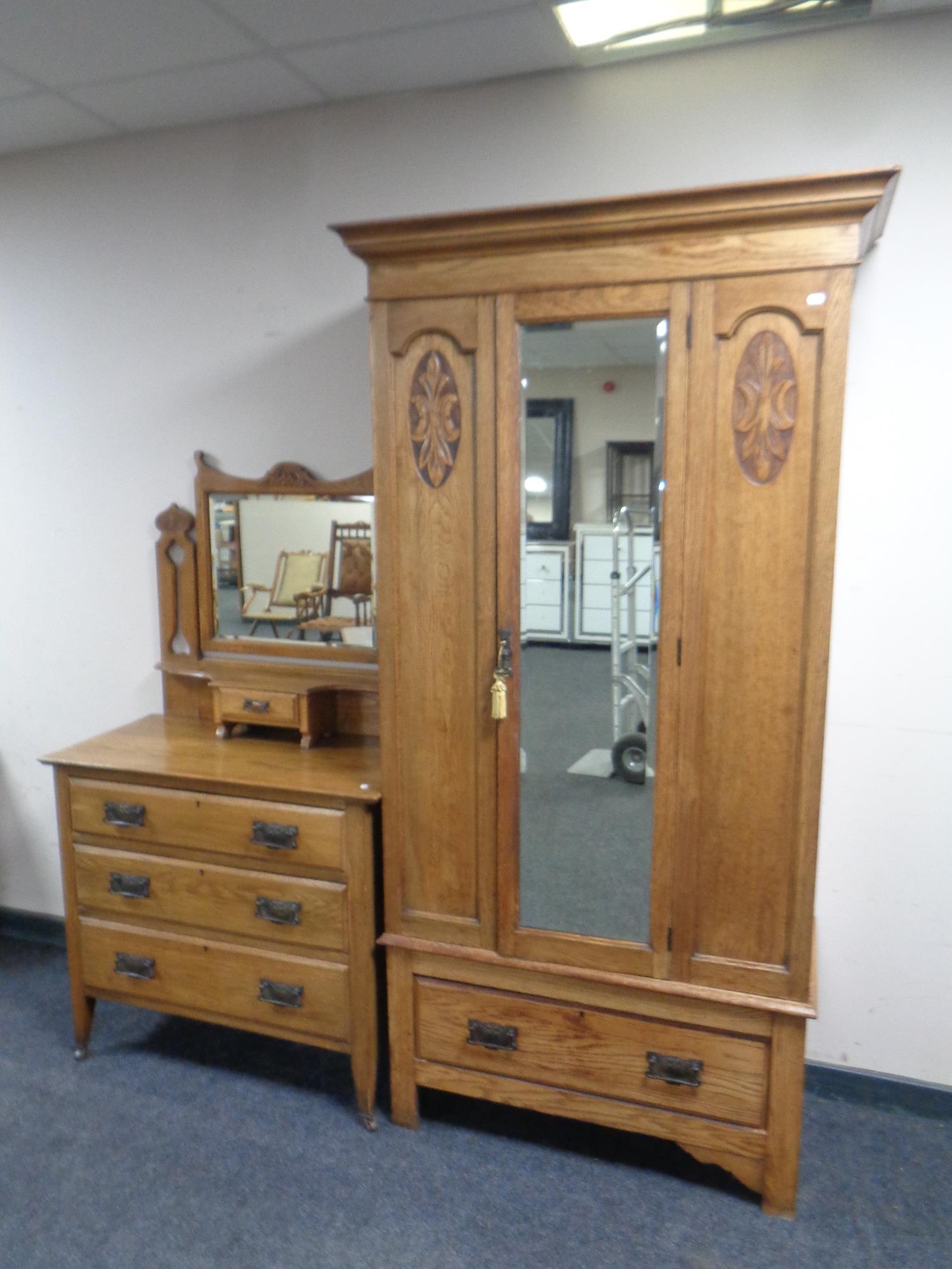 An Edwardian carved oak mirrored door wardrobe with matching mirror back dressing table fitted