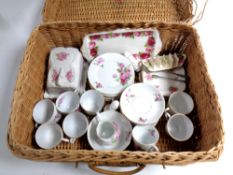 A wicker picnic basket containing a Czechoslovakian pink rose patterned tea service together with