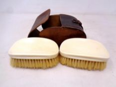 A pair of antique ivory-backed clothes brushes in leather case