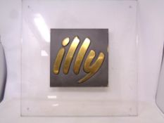An 'illy' coffee advertising brass plaque mounted in a perspex frame