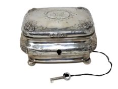 A 19th century German silver tea caddy, coat of arms to lid, on ball feet, original silver key.