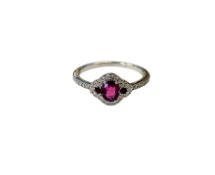 A 9ct white gold ruby three stone diamond halo ring with shoulders, size K.
