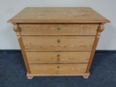An antique stripped pine four drawer chest on bun feet