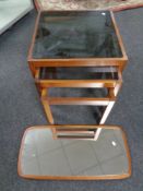 A mid 20th century nest of three smoked glass topped tables and a mirror mounted on a teak board