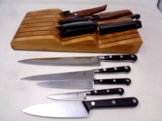 A wooden knife block containing a quantity of kitchen knives to include Sabatier, John Lewis,