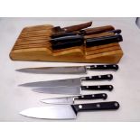 A wooden knife block containing a quantity of kitchen knives to include Sabatier, John Lewis,