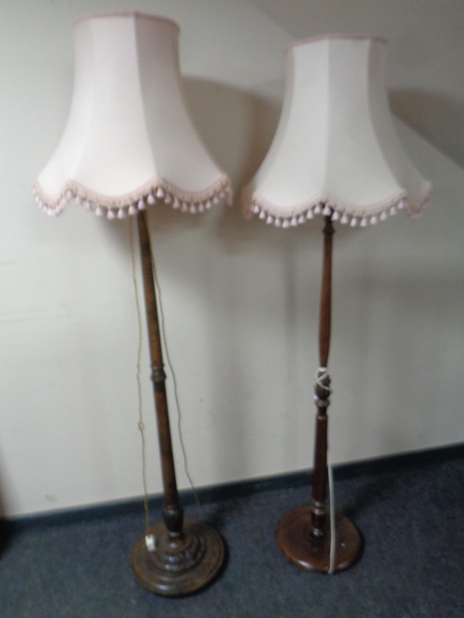Two beech wood standard lamps with pink tassel shades