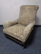 A Victorian armchair upholstered in green and gold brocade fabric