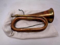 An antique copper and brass bugle in a bag