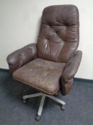 A 20th century teak framed brown button leather upholstered swivel armchair