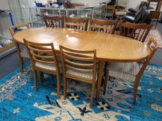 A 20th century oval teak extending dining table and six matching ladder back chairs