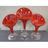 Three red plastic and chrome gas lift bar stools