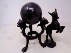 A bronze tripod stand with lion masks on paw feet holding marble sphere,