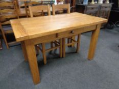 A contemporary oak farmhouse kitchen table fitted with a drawer and four ladder back chairs