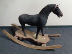 An Edwardian cloth upholstered rocking horse on wooden stand