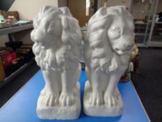 A pair of painted concrete statues, seated lions,