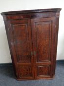 A Georgian oak double door hanging corner cupboard fitted with internal shelves and drawers