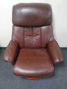 A wood framed brown leather manual reclining swivel armchair and similar footstool