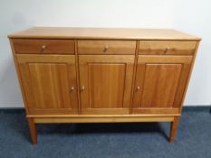 A contemporary three door three drawer sideboard on raised legs in a teak finish