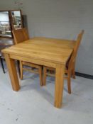 A contemporary oak square kitchen table together with a set of four matching rail back chairs