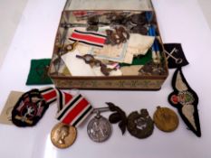 A tin containing WWI medals, cat badges, buttons and sew on badges.