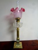 A 19th century brass Corinthian column oil lamp with etched glass cranberry shade,