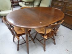 A circular extending kitchen table together with a set of four beech spindle back chairs