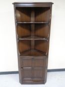 An Ercol elm and beech corner cupboard fitted shelves above