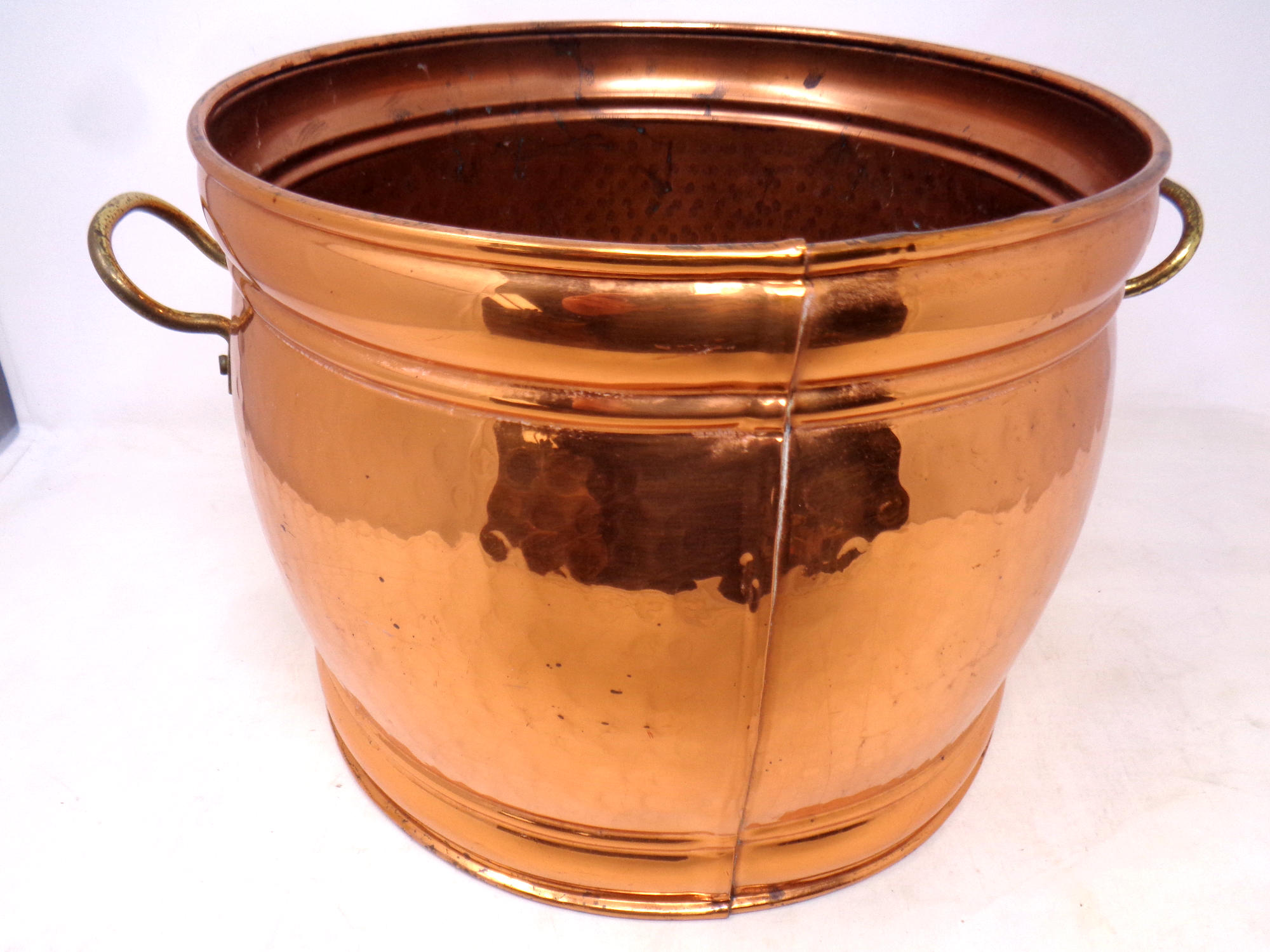 A circular copper and brass handled coal bucket