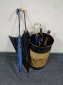 A metal stick pot containing vintage parasols and umbrellas
