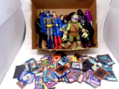 A box containing superhero figures together with a quantity of trading cards including Pokemon,
