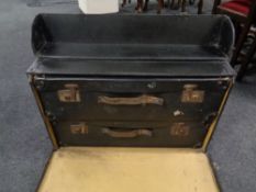 A pair of black leather suitcases contained within a larger storage trunk