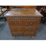 An oak linen fold three drawer chest on bun feet