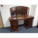 A mahogany effect bow fronted six drawer dressing table with triple mirror back
