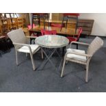 A contemporary wicker glass topped patio table and two matching armchairs