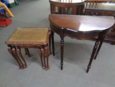 A nest of three leather and glass topped tables in a mahogany finish together with a hall table on