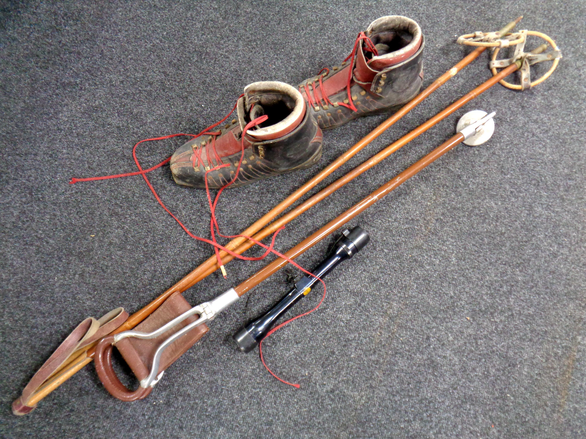 A pair of vintage bamboo ski poles, a pair of ski boots,