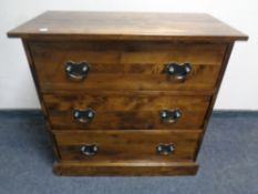 A contemporary chest of three drawers with brass drop handles