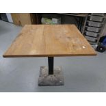 A cast iron based wooden topped square cafe table, diameter 76 cm.