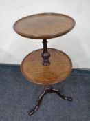 A circular mahogany two tier wine table on three way pedestal