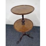 A circular mahogany two tier wine table on three way pedestal