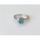 An 18ct white gold emerald and diamond cluster ring, size N CONDITION REPORT: 3.